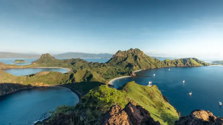 Padar Island's green hills and curved bays in Komodo National Park, seen from the rocky viewpoint at the top of the hiking trail