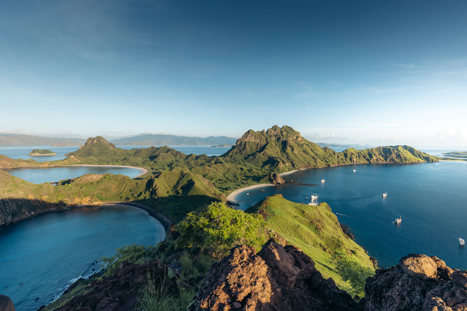 Padar Island's green hills and curved bays in Komodo National Park, seen from the rocky viewpoint at the top of the hiking trail