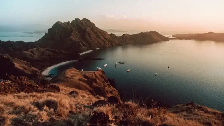 Golden hour light over savanna ridgeline hills and a bay in Komodo National Park