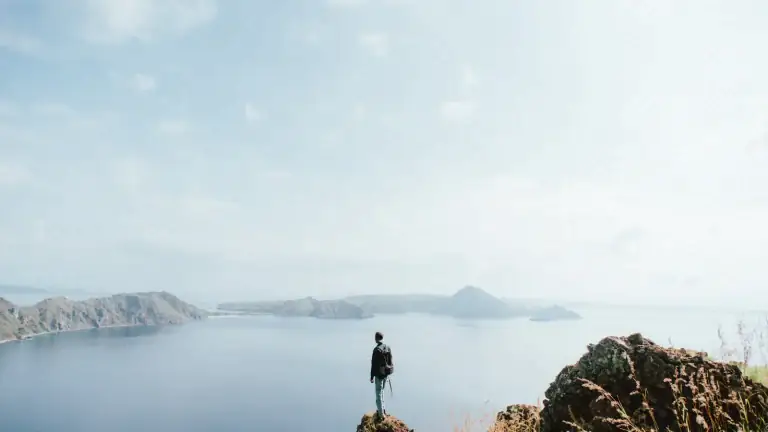 Hiker standing on the rocky ridge at Padar Island's summit, looking out over the view