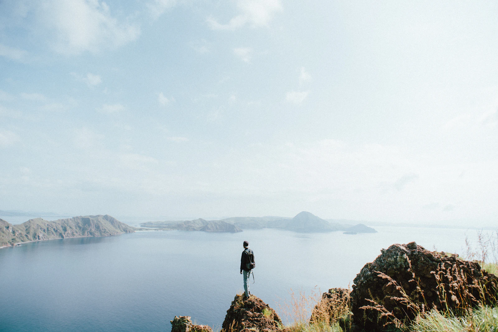 A hiker standing on the rocky summit ridge of Padar Island looking at the view below, one of the rest points along the trail