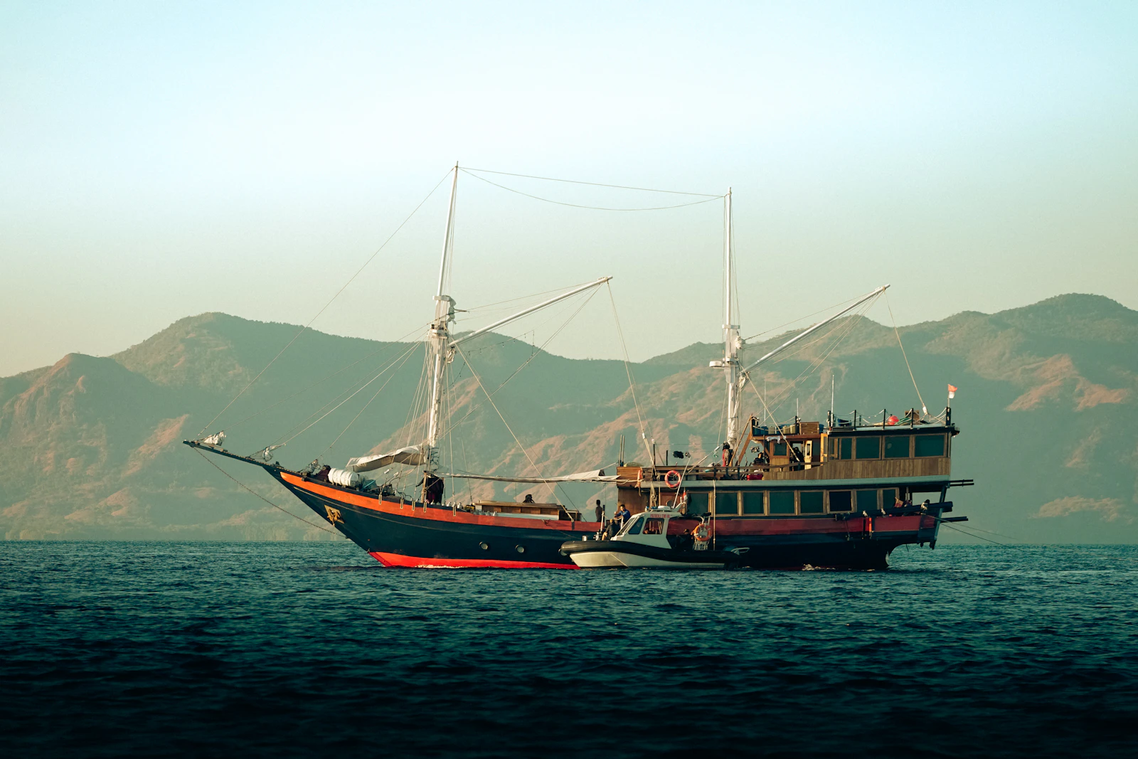 A traditional phinisi boat floating on calm water near Labuan Bajo