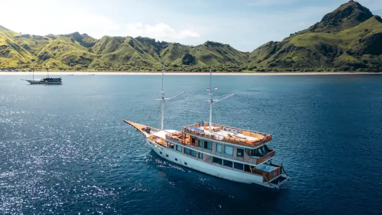 A large phinisi liveaboard floating in the waters of the Komodo area