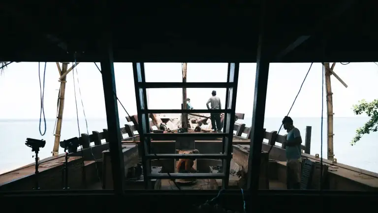 Craftsmen building a traditional wooden phinisi in a boatyard workshop