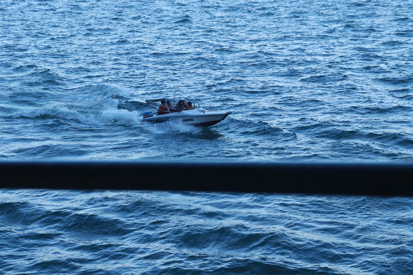 A speedboat cutting quickly through waves on open water toward Padar